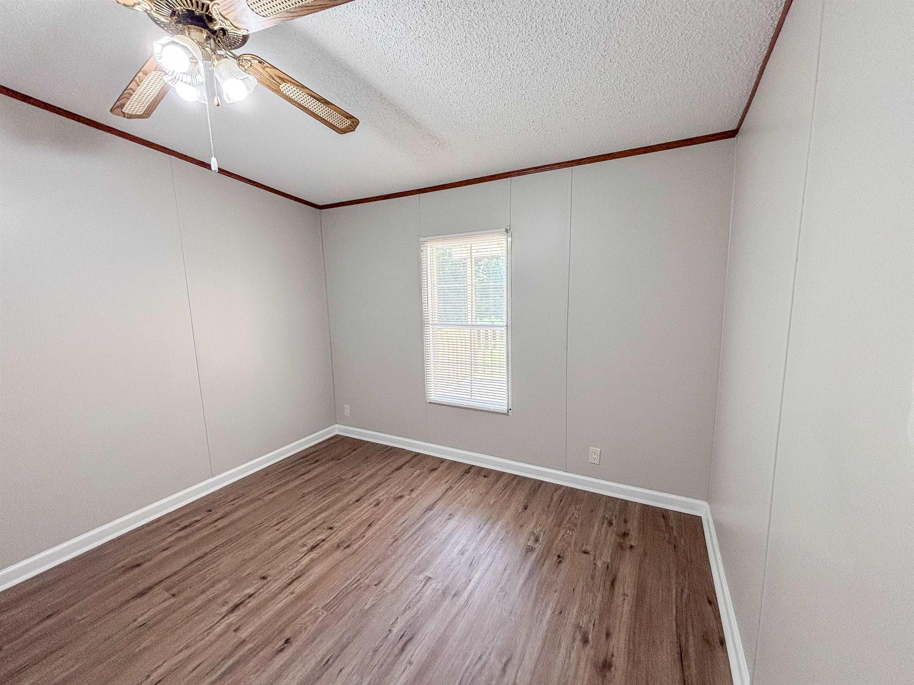 2847 Holly Grove Road Covington, TN 38019 - Photo 26 of 36 Room featuring wood-finish flooring, light gray wall panels, white baseboards, and a window with a white frame