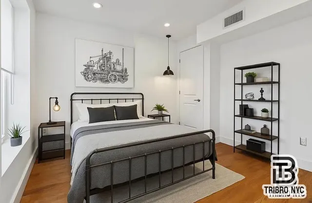 a bedroom with a bed paintings on the wall and a window