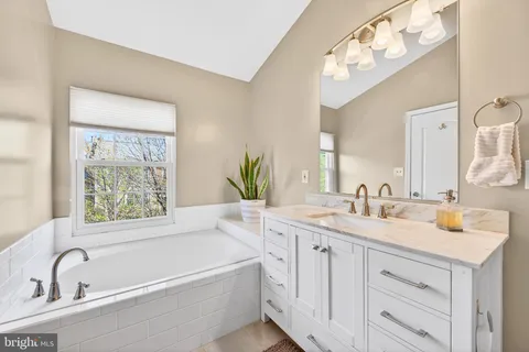a bathroom with a tub a sink and mirror
