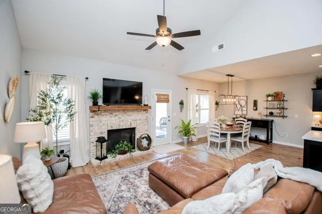 a kitchen with stainless steel appliances kitchen island granite countertop a refrigerator a sink dishwasher a dining table and chairs with wooden floor