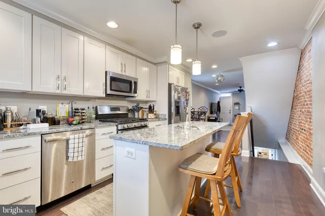 a kitchen with stainless steel appliances granite countertop a stove top oven a sink a dining table and chairs with wooden floor