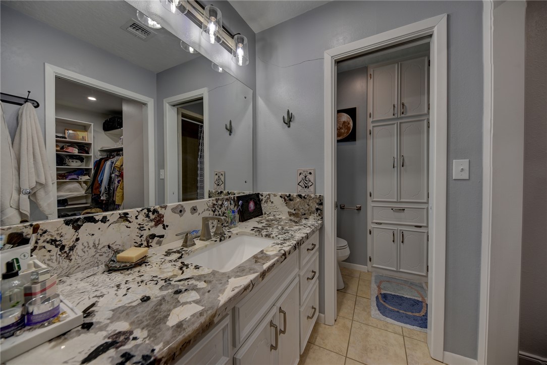 1600 Pecan Street Brenham, TX 77833 - Photo 13 of 33 Full bathroom featuring granite counter top, a walk in closet, toilet and tile shower