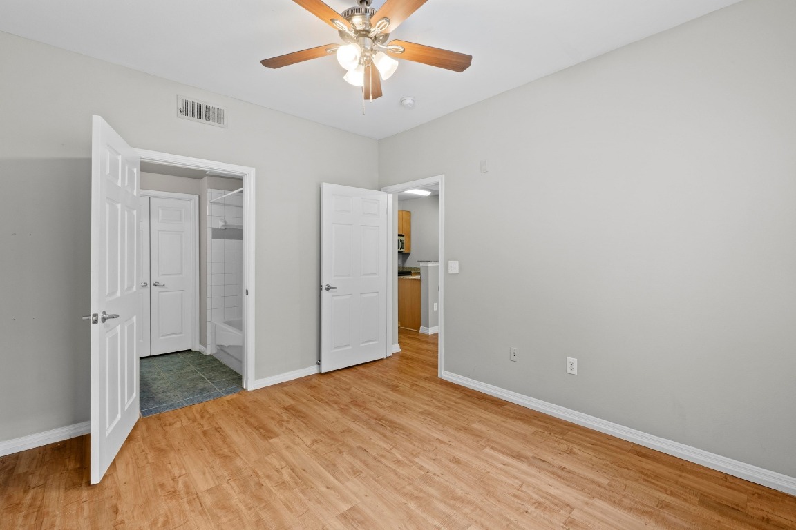 2502 Leon Street, Unit 213 Austin, TX 78705 - Photo 11 of 20 Unfurnished bedroom featuring ensuite bath, light wood-style flooring, and ceiling fan