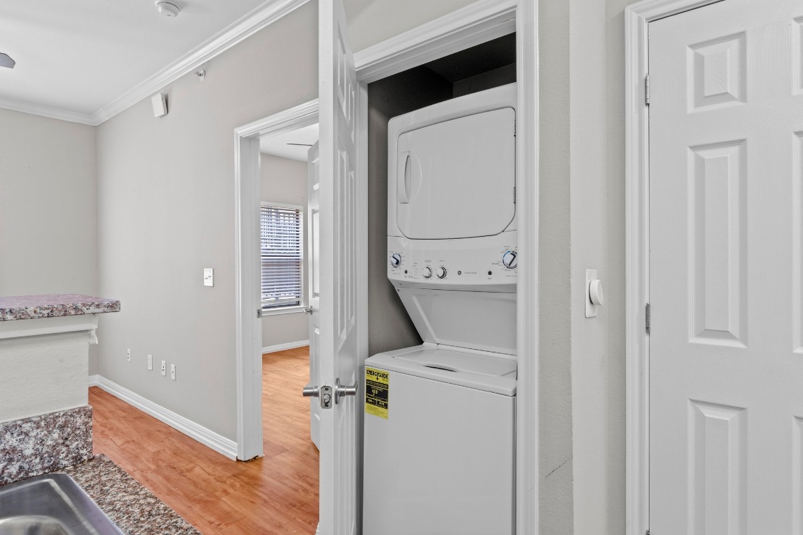 2502 Leon Street, Unit 213 Austin, TX 78705 - Photo 16 of 20 Laundry room featuring estacked washer and dryer, light wood-type flooring, and crown molding