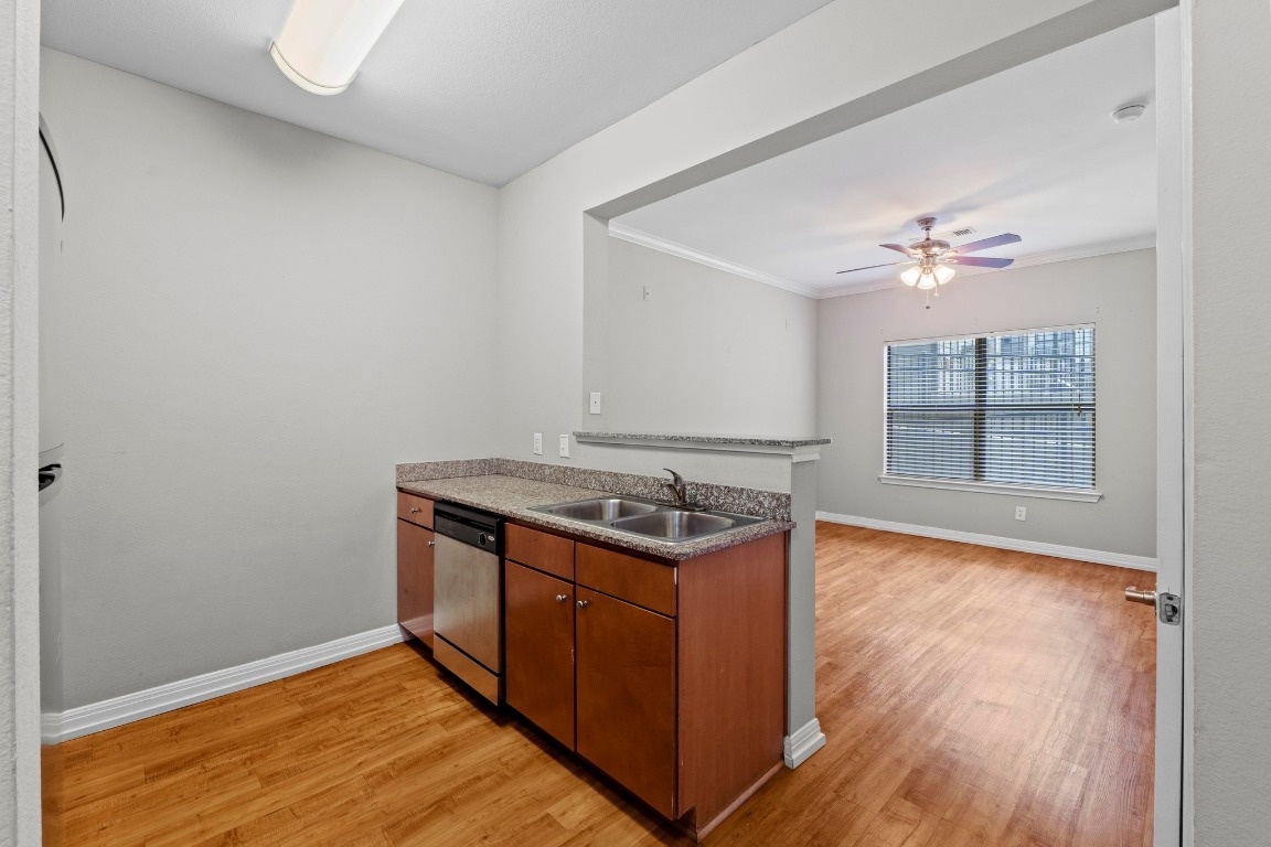 2502 Leon Street, Unit 213 Austin, TX 78705 - Photo 2 of 20 Kitchen featuring brown cabinetry, dishwasher, light wood-style flooring, a peninsula, and crown molding