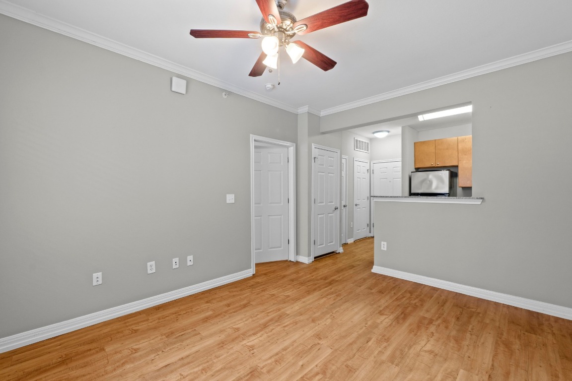 2502 Leon Street, Unit 213 Austin, TX 78705 - Photo 5 of 20 Unfurnished room featuring ornamental molding, light wood finished floors, and a ceiling fan