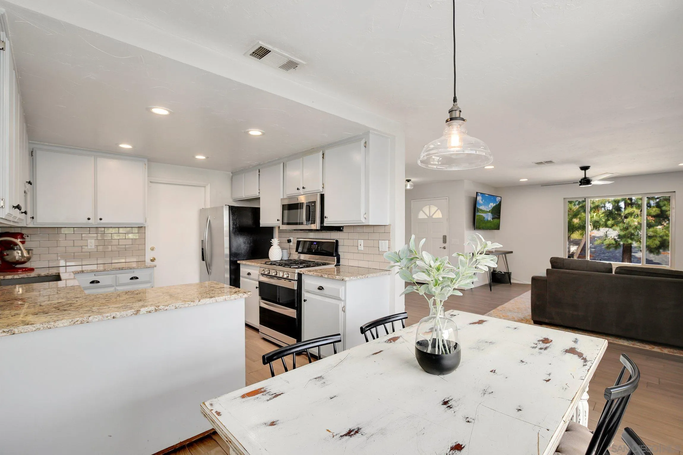 320 Grapevine Road, Unit 15 Vista, CA 92083 - Photo 2 of 18 a kitchen with a dining table chairs stove and white cabinets