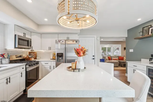 a kitchen with stainless steel appliances granite countertop a sink dishwasher stove refrigerator and couches with wooden floor