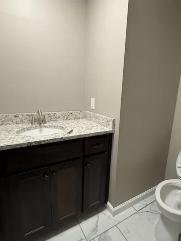 a bathroom with a granite countertop sink and a toilet