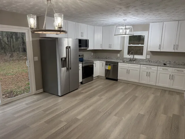 a kitchen with stainless steel appliances granite countertop a refrigerator a stove top oven a sink and dishwasher