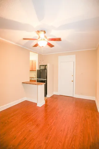 a view of kitchen and empty room with wooden floor