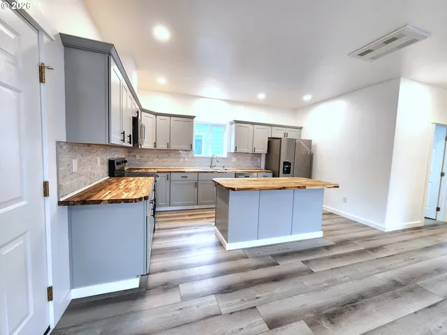 a large kitchen with stainless steel appliances granite countertop a stove a sink dishwasher and a refrigerator with wooden floor