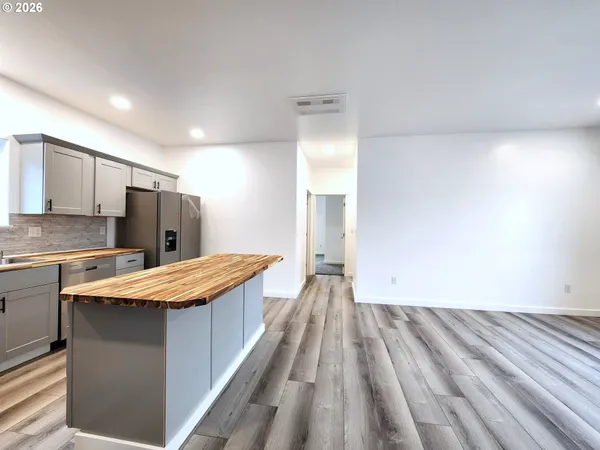 a large kitchen with kitchen island a stove a sink dishwasher and a refrigerator with wooden floor
