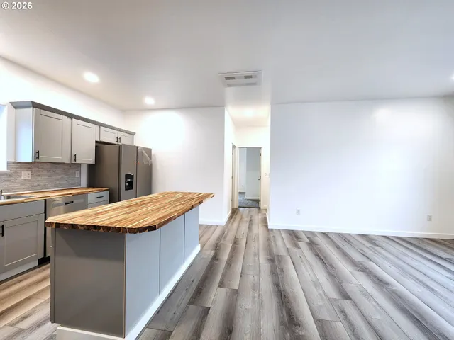 a large kitchen with kitchen island a stove a sink dishwasher and a refrigerator with wooden floor