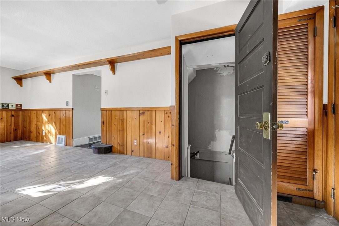 19560 Lorain Road Cleveland, OH 44126 - Photo 21 of 35 Empty room with wainscoting, tile patterned flooring, wood walls, and beamed ceiling