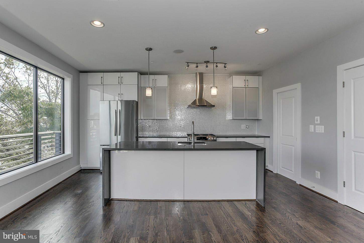 1839 6th Street Northwest, Unit 4 Washington, DC 20001 - Photo 21 of 29 a large kitchen with stainless steel appliances a large counter top a sink a stove a refrigerator and cabinets
