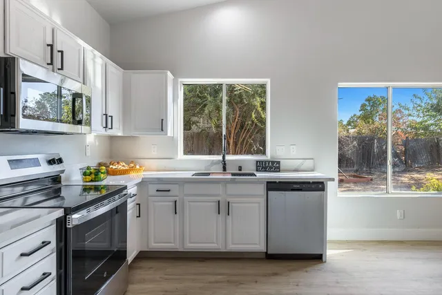 a kitchen with stainless steel appliances granite countertop a stove a sink and a granite counter tops with wooden floors
