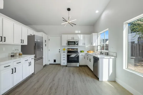 a kitchen with stainless steel appliances a refrigerator a stove top oven a sink dishwasher and a refrigerator with wooden floor