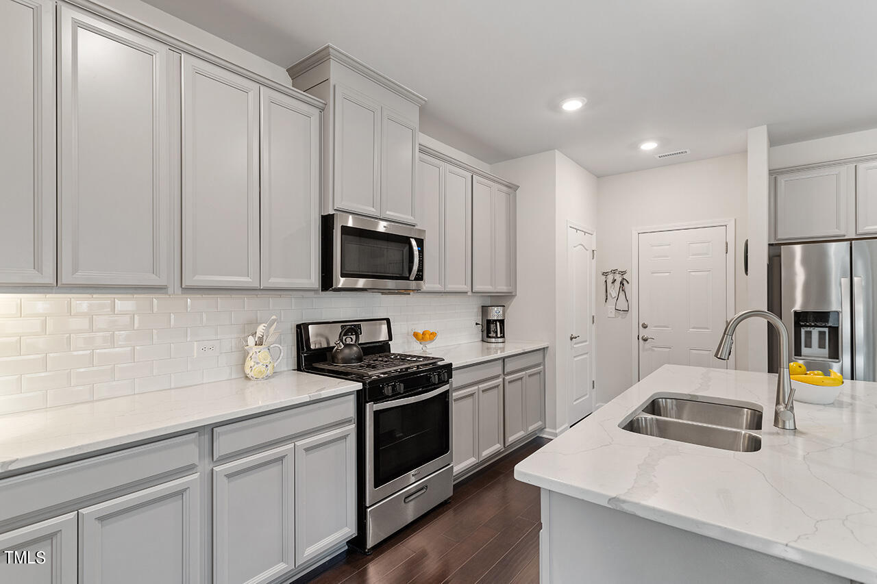 1157 Chestnut Bluff Apex, NC 27502 - Photo 8 of 42 a kitchen with white cabinets and stainless steel appliances