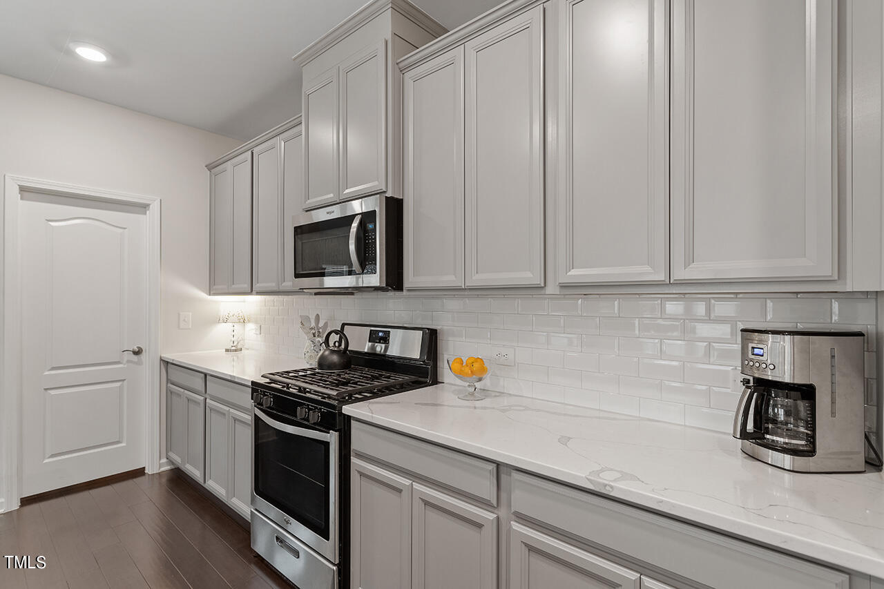 1157 Chestnut Bluff Apex, NC 27502 - Photo 9 of 42 a kitchen with granite countertop white cabinets stainless steel appliances and wooden floor