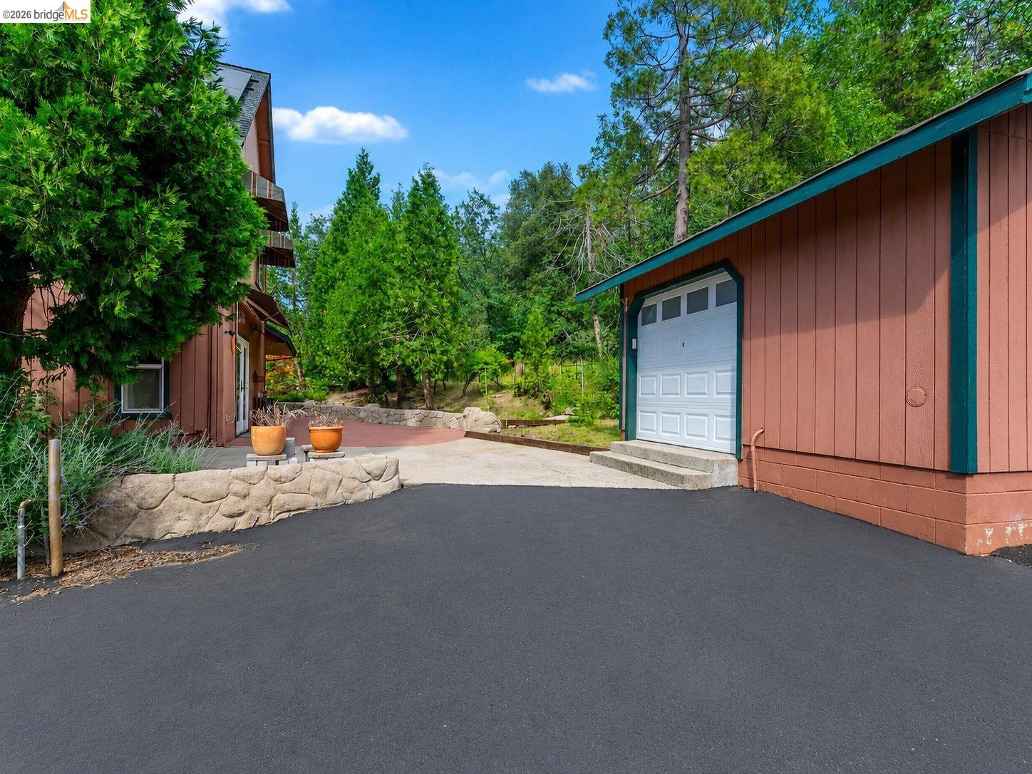 22401 Ridge Road Twain Harte, CA 95383 - Photo 42 of 56 Attached garage with a white panel door, asphalt driveway, and a stone-clad retaining wall