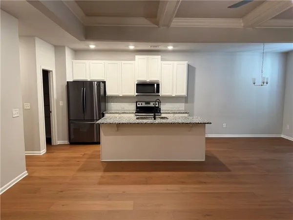 a view of kitchen with stainless steel appliances wooden floor and window
