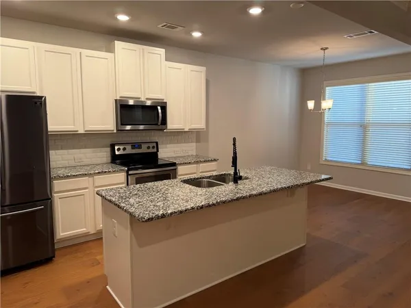 a kitchen with kitchen island granite countertop a sink appliances and cabinets