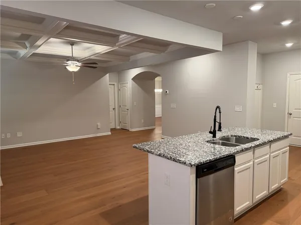 a kitchen with a sink granite counter tops and a wooden floor