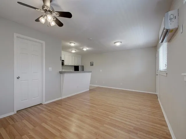 a view of an empty room with a window and wooden floor