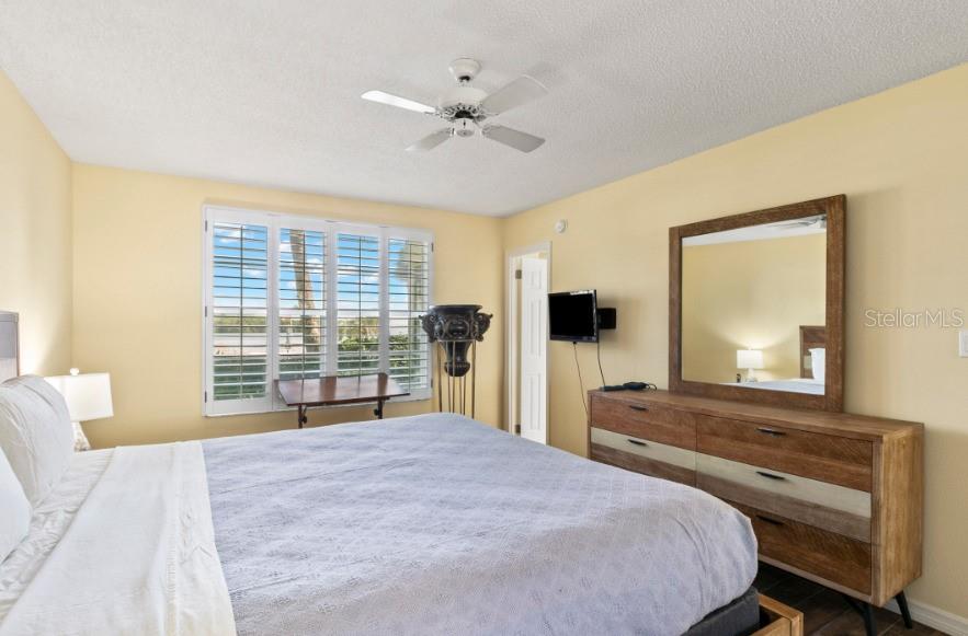 605 Sutton Place, Unit 102 Longboat Key, FL 34228 - Photo 13 of 29 a bedroom with a bed and a large window with balcony view
