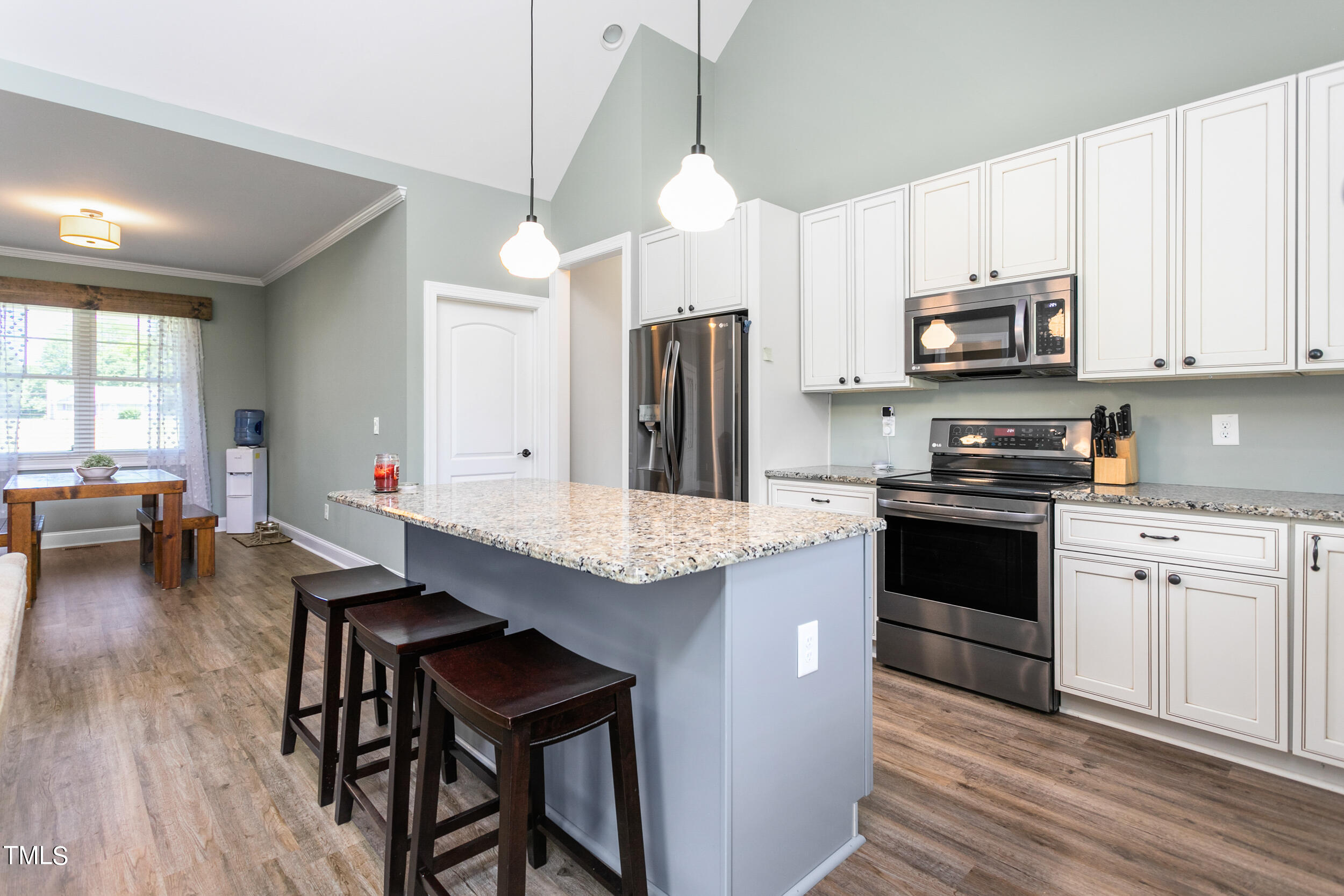 4455 Boyd Wright Road Burlington, NC 27215 - Photo 18 of 40 a kitchen with kitchen island granite countertop a stove a sink a refrigerator and white cabinets with wooden floor