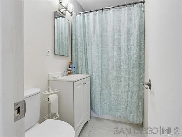 9462 Doheny Road Santee, CA 92071 - Photo 16 of 33 a bathroom with a sink a toilet a mirror and shower curtain