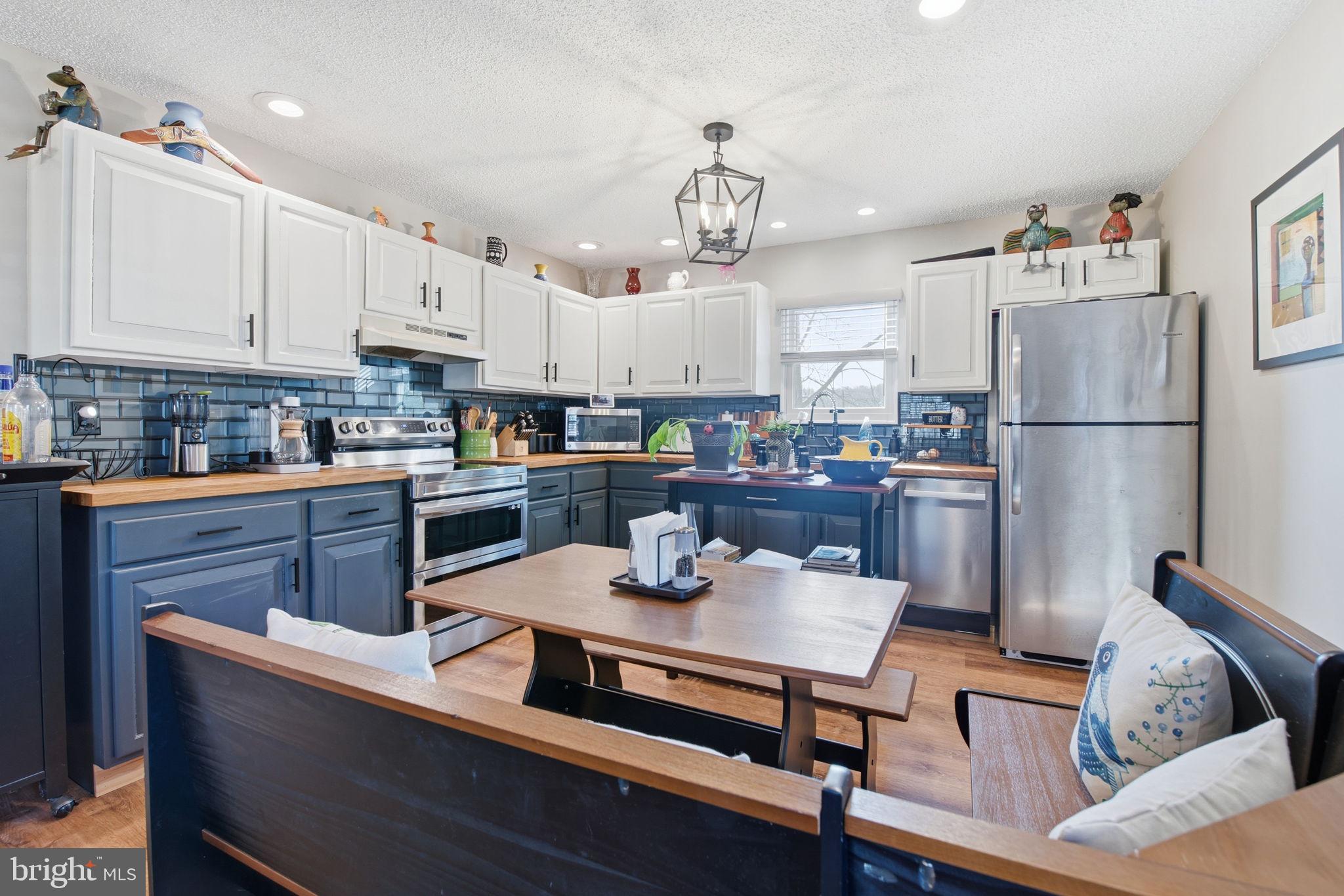 6501 Fair School Road Glen Rock, PA 17327 - Photo 33 of 43 a kitchen with a refrigerator a stove a sink dishwasher and white cabinets with wooden floor