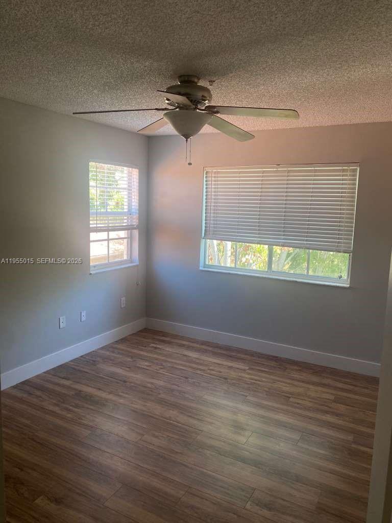 7930 North Nob Hill Road, Unit 304 Tamarac, FL 33321 - Photo 14 of 30 an empty room with wooden floor fan and windows