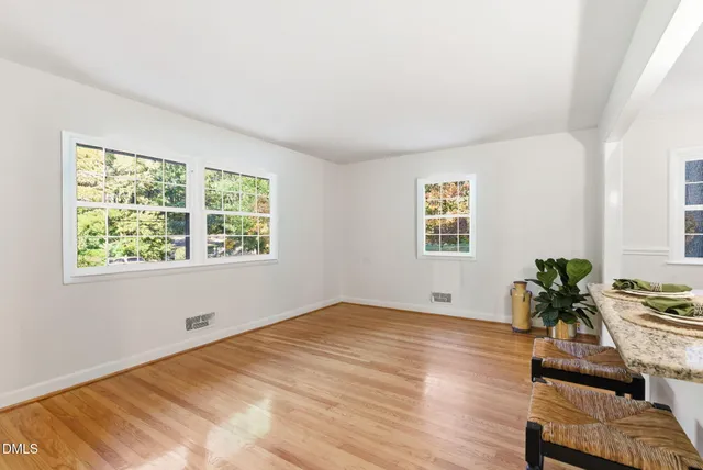a view of an empty room with window and wooden floor