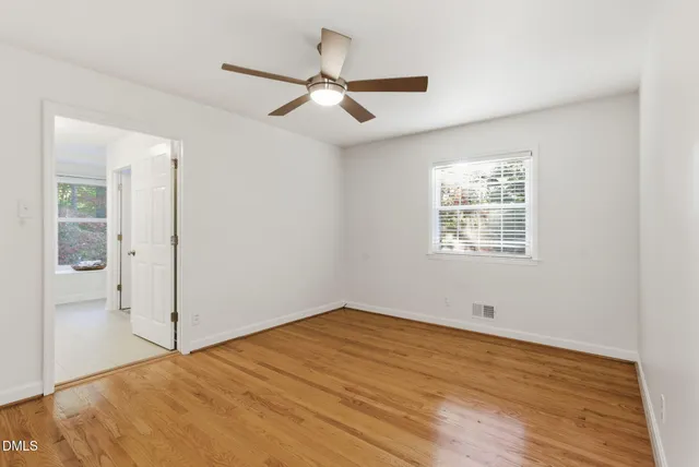an empty room with wooden floor and fireplace