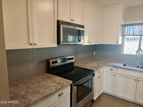 a kitchen with granite countertop white cabinets and a stove