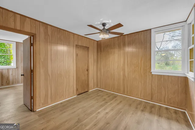 a view of empty room with wooden floor and fan