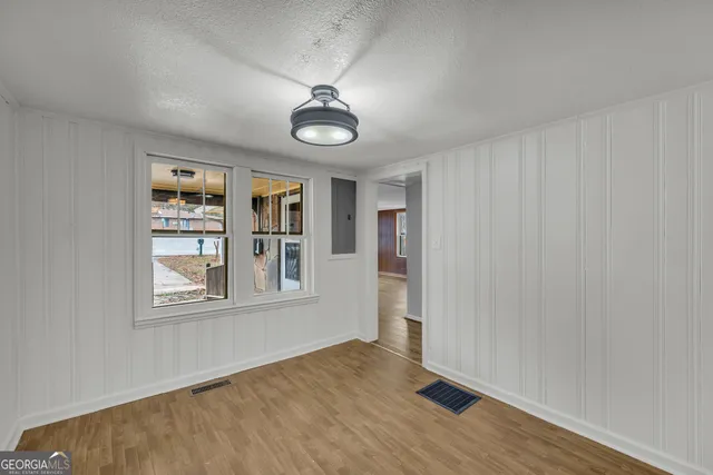 an empty room with wooden floor chandelier fan and windows