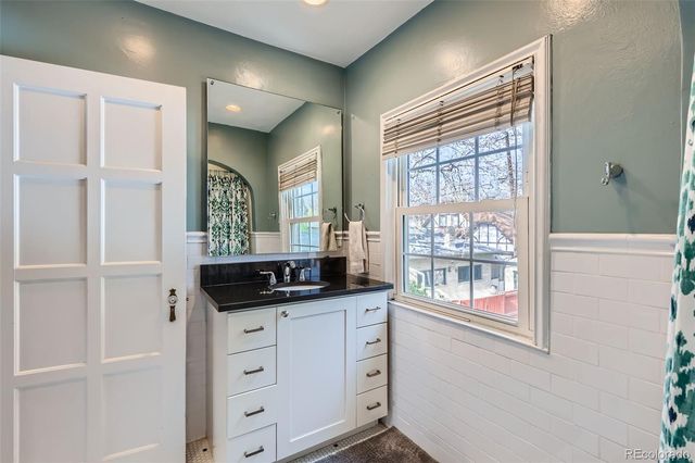 a bathroom with a granite countertop sink and a window