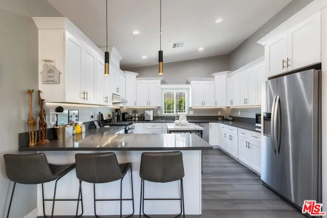 a kitchen with stainless steel appliances granite countertop a stove a sink a center island and a window