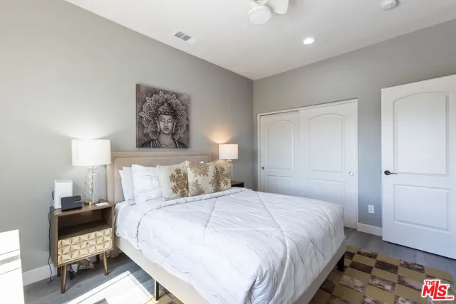 a bedroom with a bed a mirror on dresser and a chandelier