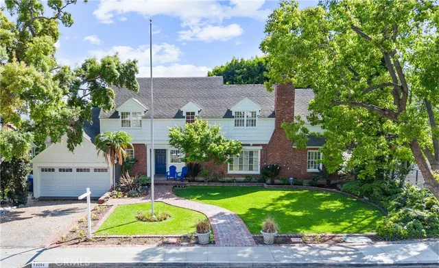 a view of a house with a small yard plants and large tree