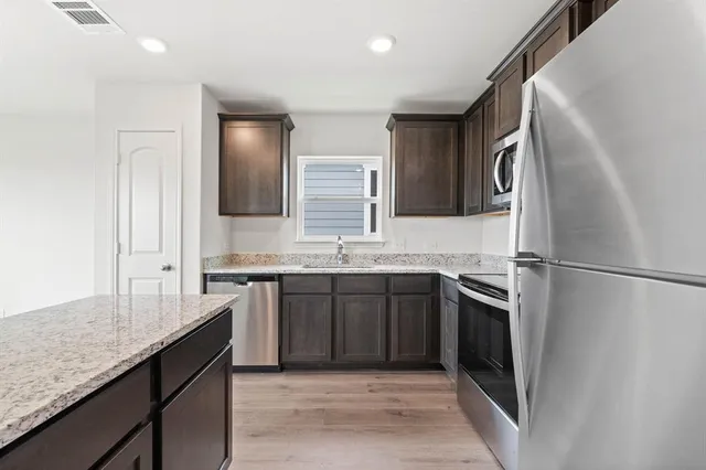 a large kitchen with a granite countertop refrigerator sink and stove
