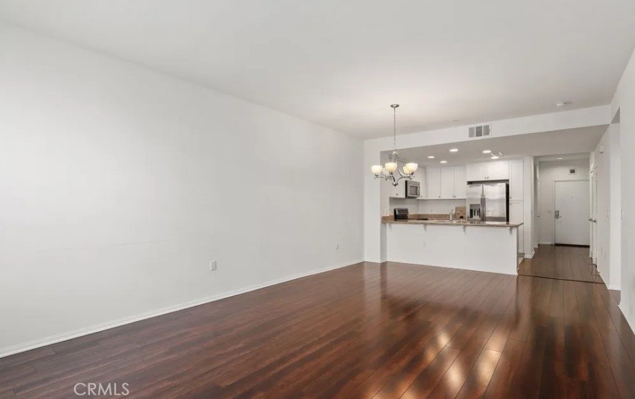a view of a living room hardwood floor and a view of kitchen