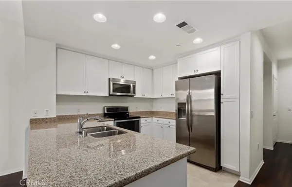 a kitchen with stainless steel appliances granite countertop a refrigerator a stove and a sink
