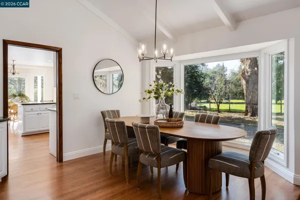 a kitchen with stainless steel appliances granite countertop a stove top oven a sink a dining table and chairs
