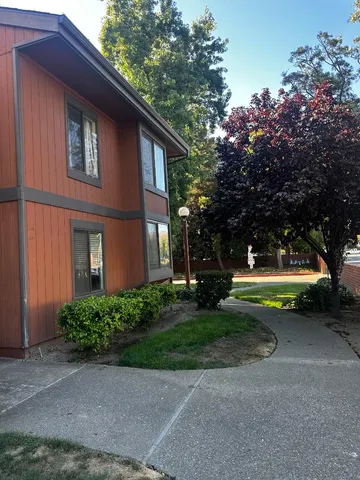 a small garden with a bench in front of the house