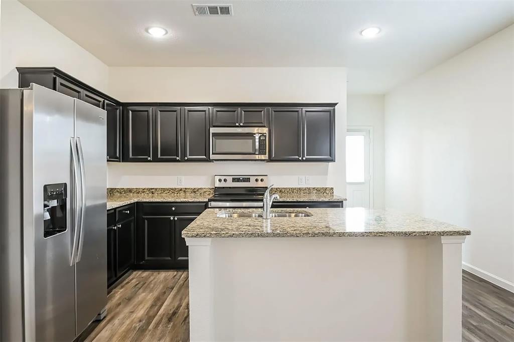 6214 Old Bridge Way Forney, TX 75126 - Photo 4 of 15 a kitchen with stainless steel appliances granite countertop a refrigerator a stove a sink and a microwave