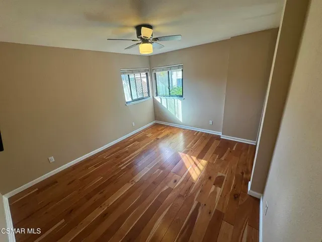 a view of empty room with wooden floor and fan